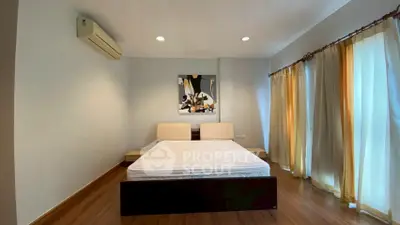 Spacious bedroom with modern decor and large windows for natural light.