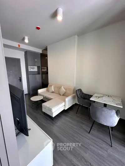 Modern living room with sleek furniture and dining area in a stylish apartment.
