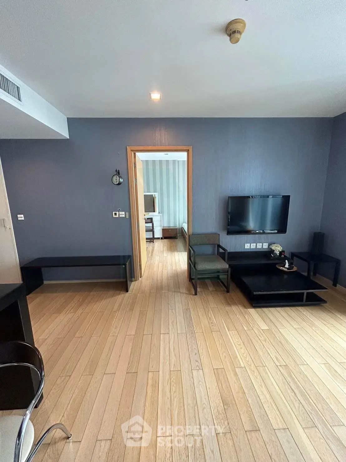 Modern living room with wooden flooring and wall-mounted TV in a stylish apartment.