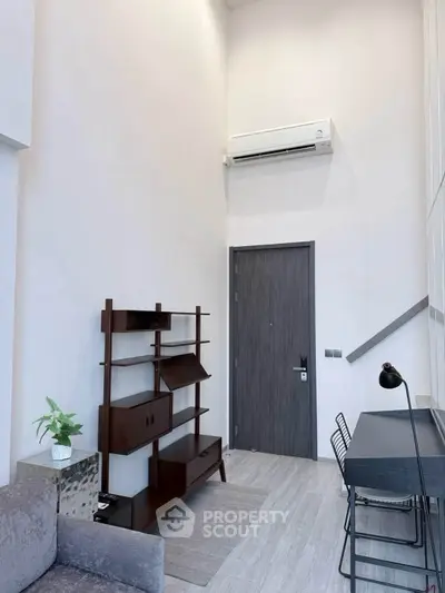 Modern living room with high ceiling, stylish furniture, and air conditioning unit.