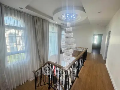 Elegant staircase with modern chandelier in a bright, spacious home interior.