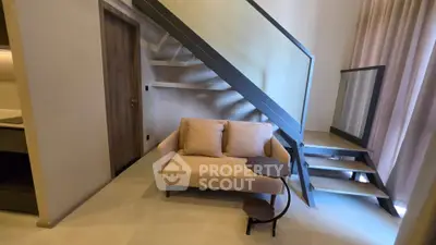 Modern living room with stylish staircase and cozy sofa in contemporary apartment.