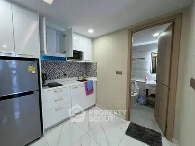 Modern kitchen with sleek cabinetry and adjacent bathroom in a stylish apartment.