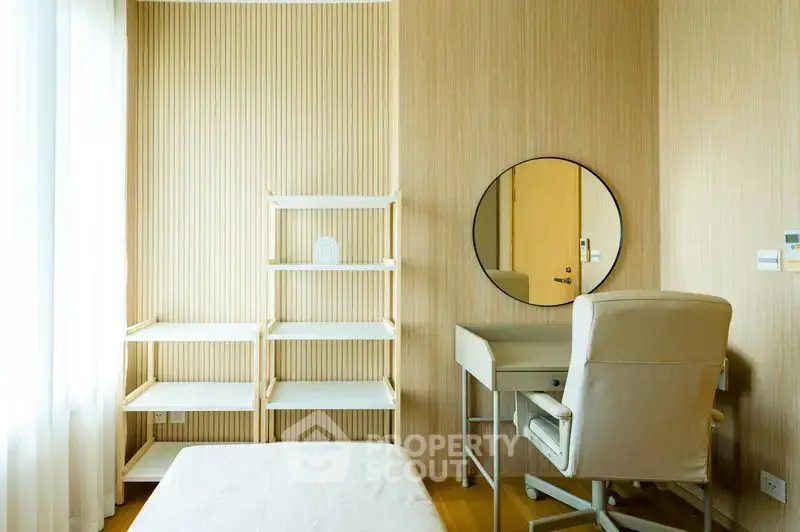 Modern bedroom with stylish desk and chair, featuring a round mirror and natural light.