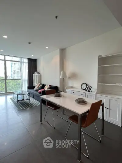 Modern living room with sleek furniture and large windows offering city views.