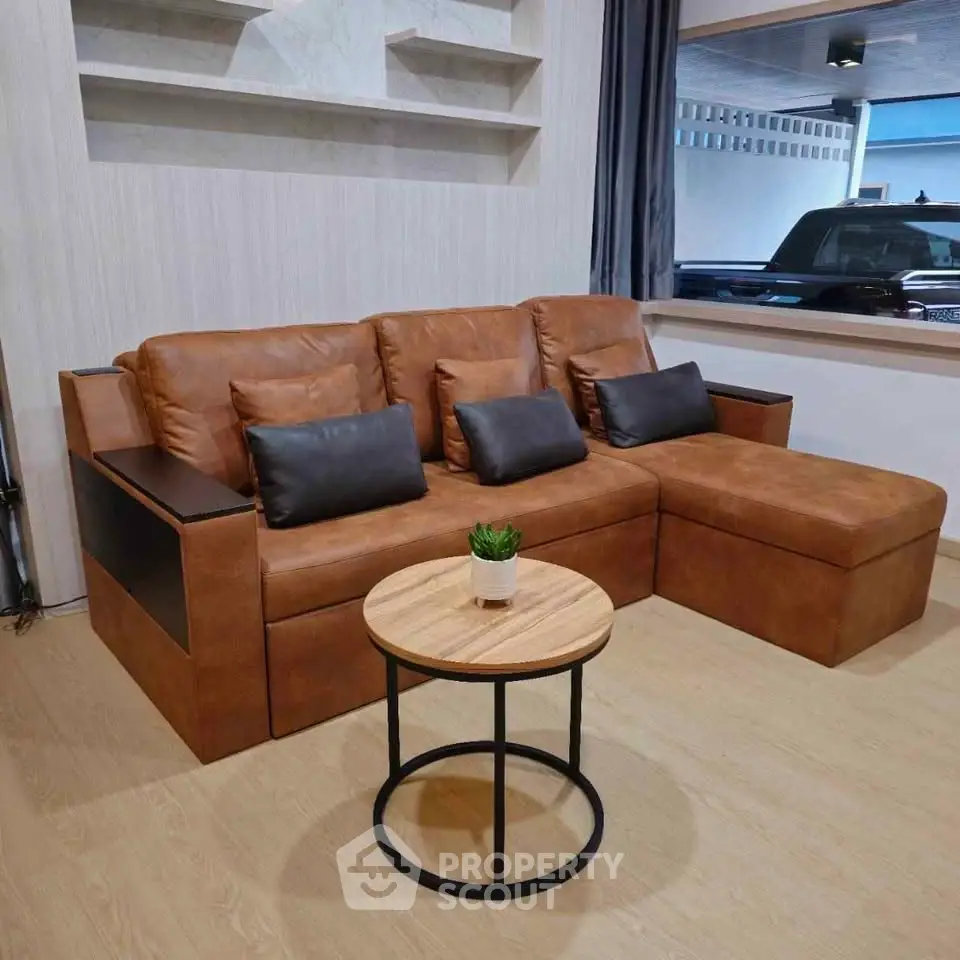 Modern living room with stylish brown leather sectional sofa and round wooden coffee table.