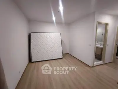 Spacious empty bedroom with wooden flooring and attached bathroom, ready for customization.