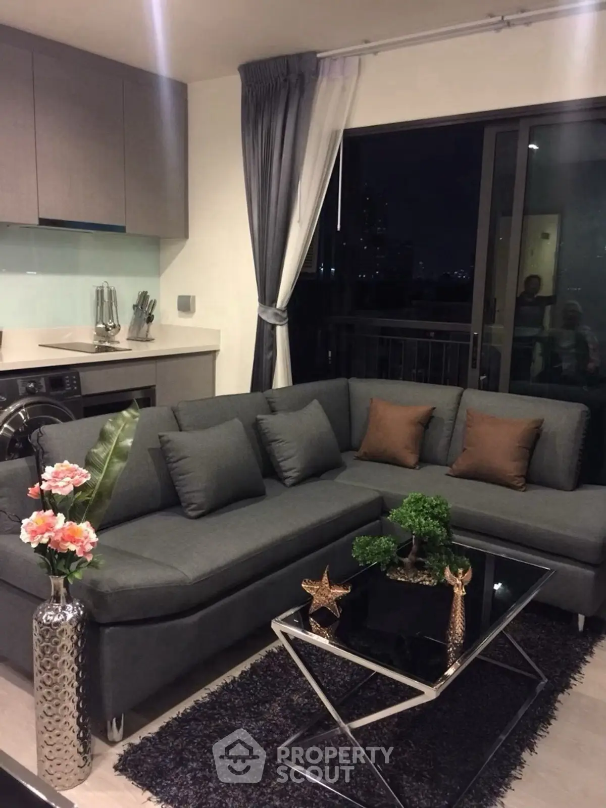 Modern living room with stylish decor and city view, featuring a sleek gray sofa and elegant coffee table.