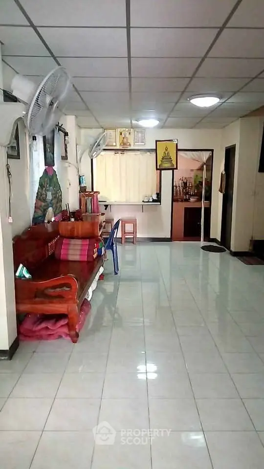 Spacious living room with tiled floor and wooden furniture, featuring ceiling fans and a cozy atmosphere.