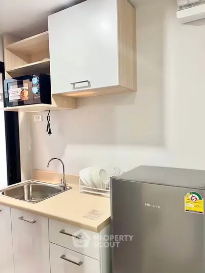 Modern kitchen with compact fridge and sleek cabinetry in a stylish apartment.