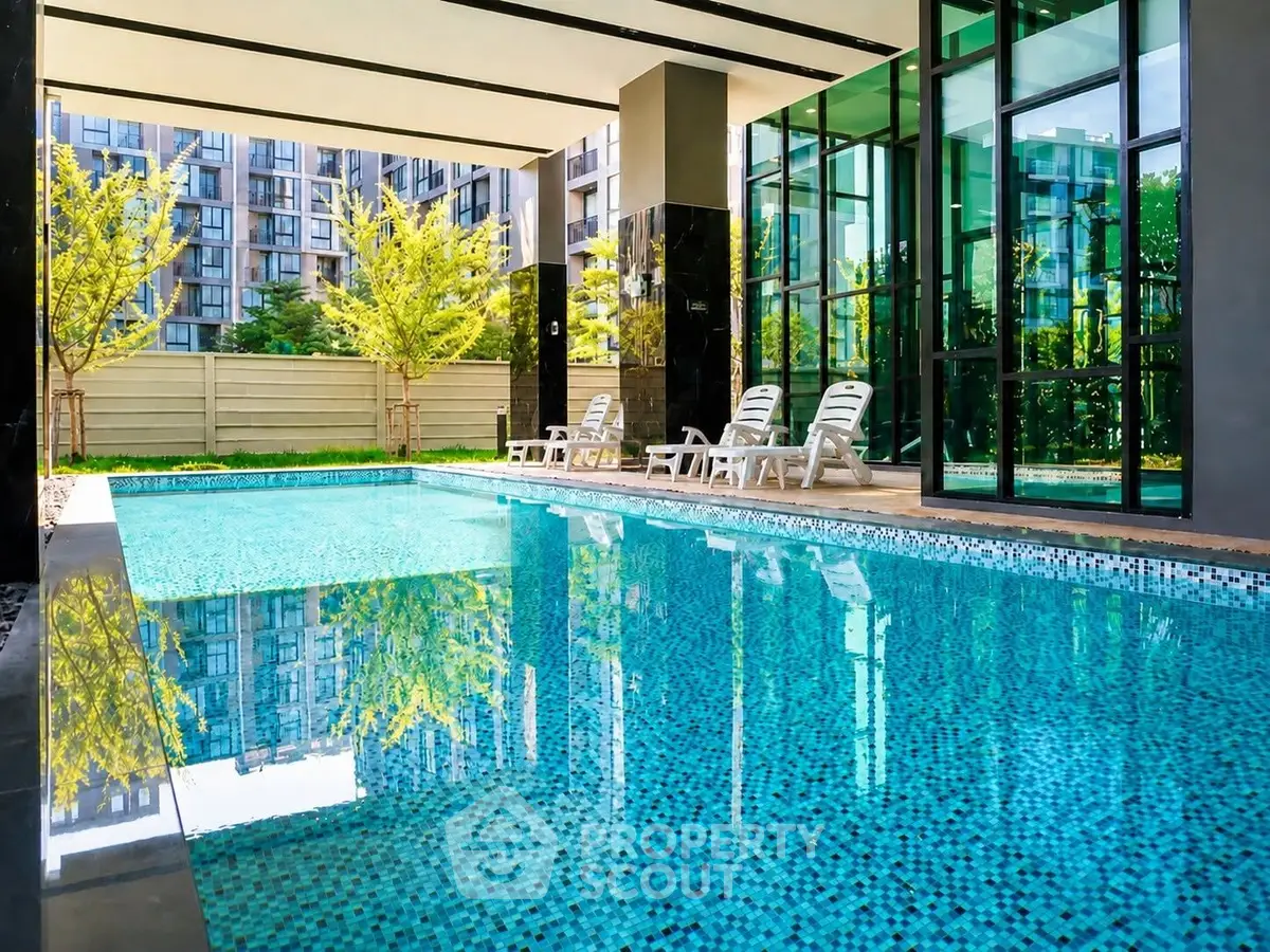 Luxurious modern apartment pool with sun loungers and lush greenery, perfect for relaxation and leisure.