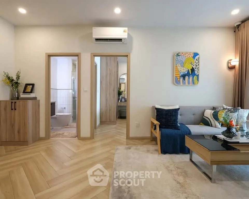 Modern living room with stylish decor and open view to bathroom, featuring cozy seating and elegant flooring.