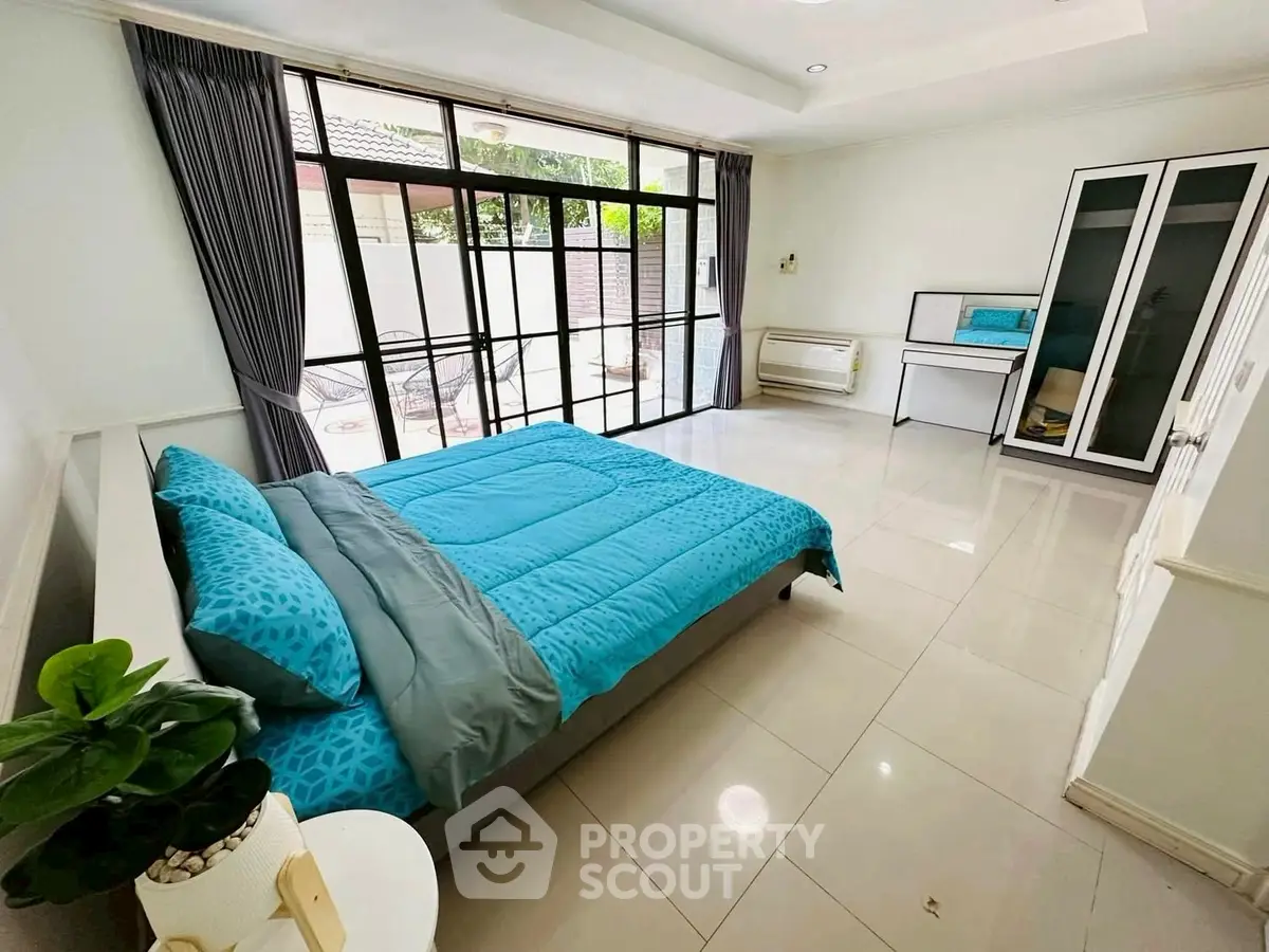 Spacious bedroom with modern decor and large windows for natural light.