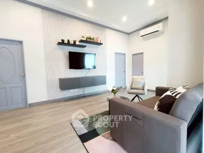 Modern living room with stylish decor, wall-mounted TV, and comfortable seating in a contemporary apartment.