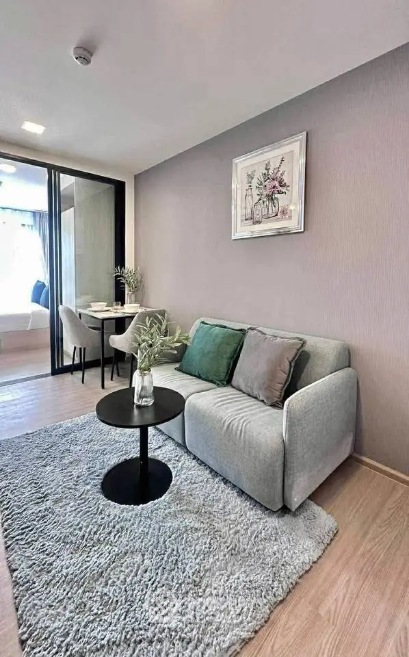 Modern living room with cozy sofa, stylish decor, and dining area in open layout apartment.