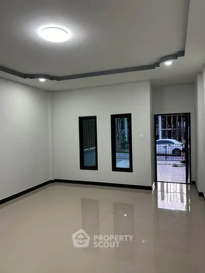 Spacious empty room with large windows and modern lighting, ideal for customization.