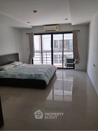 Spacious bedroom with large window and modern decor in urban apartment