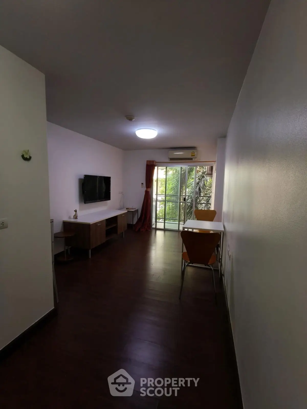 Spacious living room with dark wood flooring and balcony access, perfect for modern living.