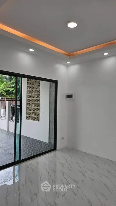 Modern interior with marble flooring and sliding glass doors leading to a spacious balcony.