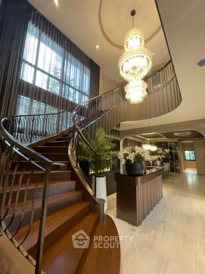 Luxurious grand staircase with elegant chandelier in a spacious living area, perfect for upscale living.