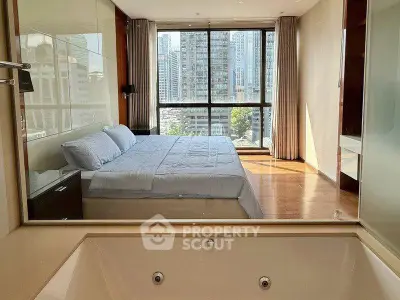 Luxurious bedroom with city view and ensuite bathtub in modern high-rise apartment.