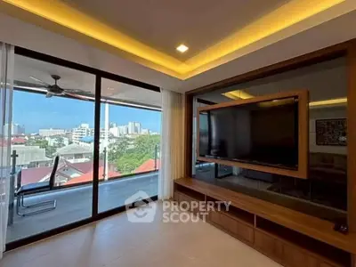 Spacious living room with modern entertainment setup and balcony view