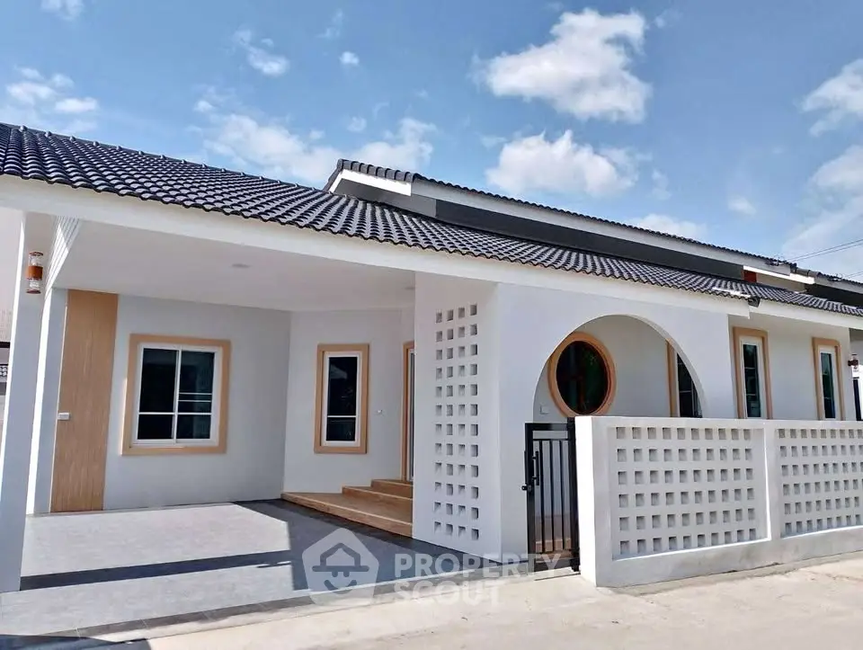 Modern single-story house with unique circular window and spacious driveway.