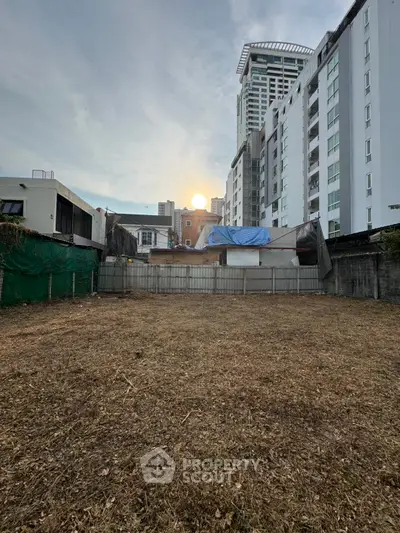 Vacant land with urban backdrop, ideal for development in a bustling city area.
