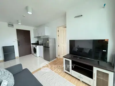 Modern living room with sleek furniture and compact kitchen in open layout apartment.