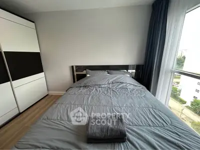 Modern bedroom with sleek design, featuring a cozy bed and large window with city view.