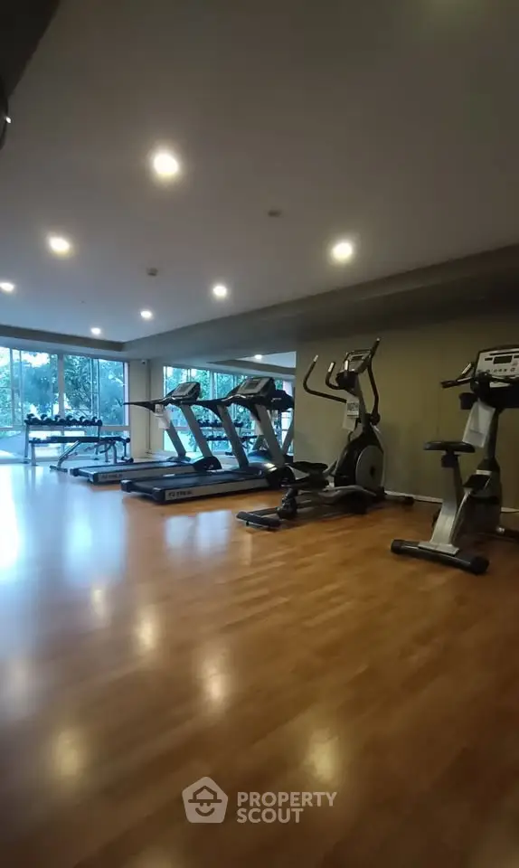 Spacious gym with modern equipment and large windows offering a serene view, perfect for fitness enthusiasts.