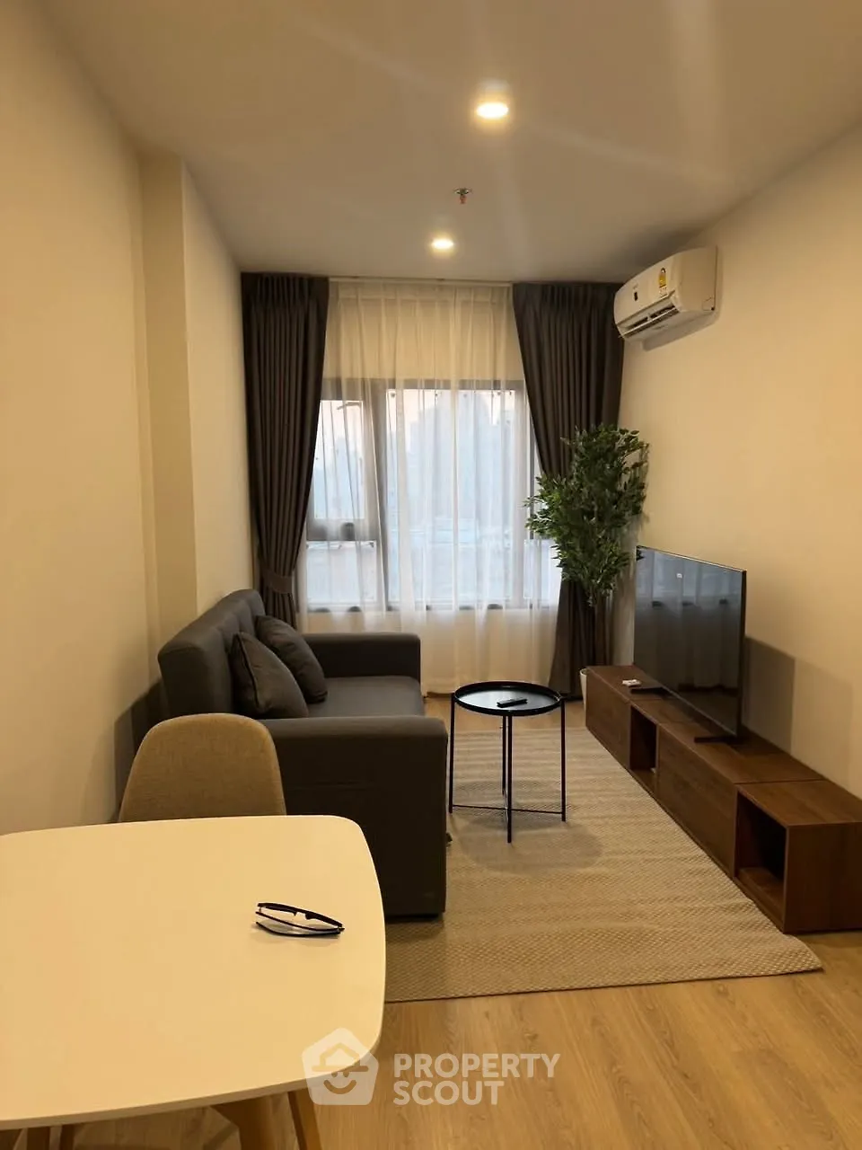 Modern living room with cozy sofa, TV, and air conditioning in stylish apartment.