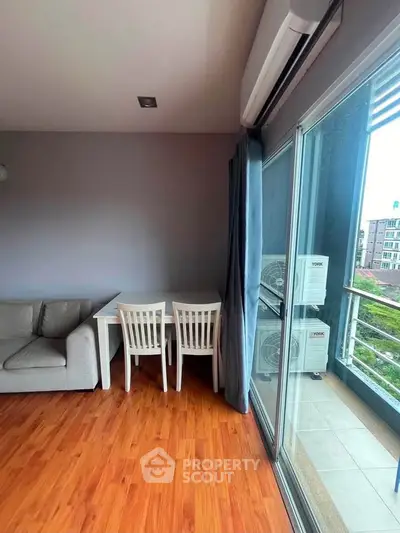 Modern living room with wooden flooring, cozy sofa, and balcony view