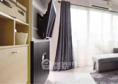 Modern living room with sleek TV setup and large window for natural light.