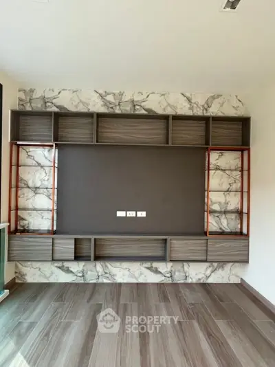 Modern living room with stylish built-in shelving and marble accent wall.