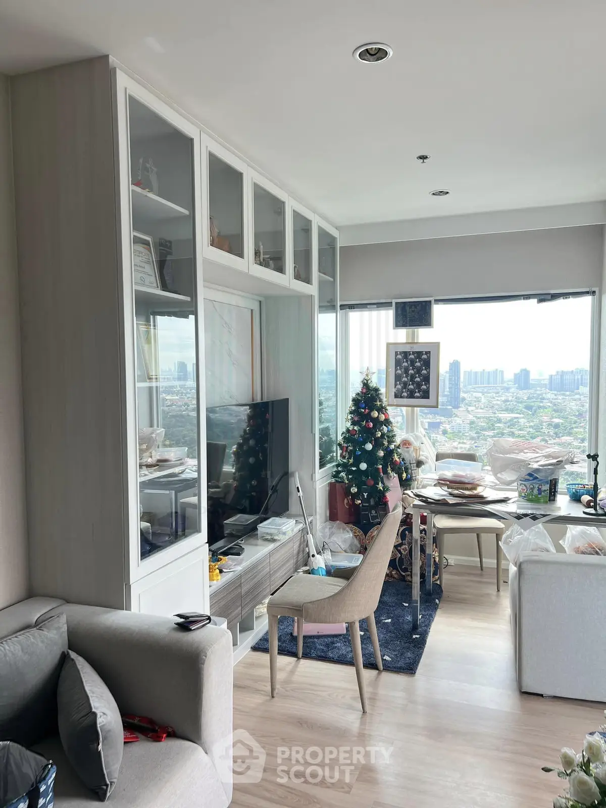Modern living room with city view, stylish furniture, and festive decor in a high-rise apartment.
