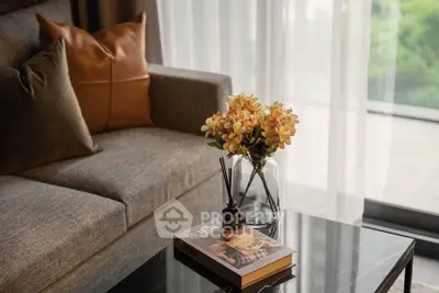 Stylish living room with modern sofa, elegant coffee table, and decorative flowers by a large window.
