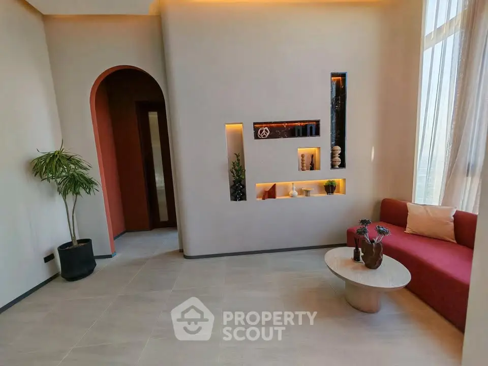 Modern living room with stylish decor and natural light, featuring a cozy seating area and elegant shelving.