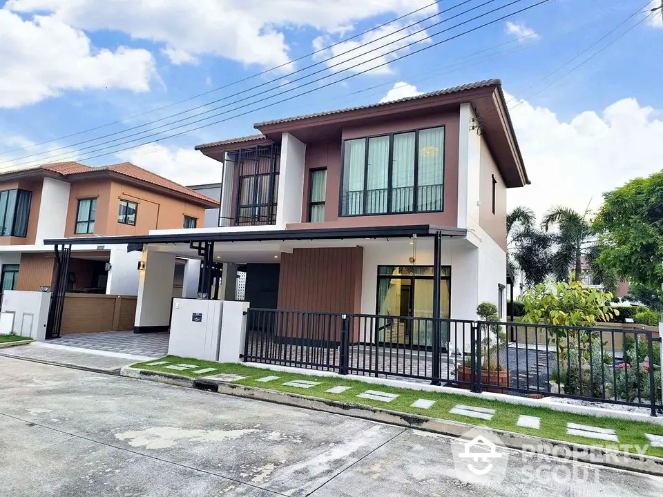 Modern two-story house with sleek design and spacious driveway in suburban neighborhood.