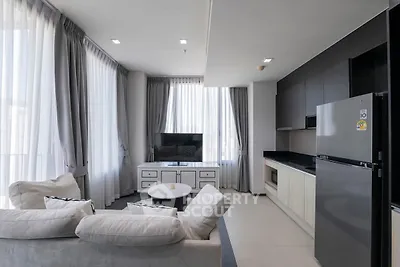 Modern living room with sleek kitchen and large windows in a stylish apartment.