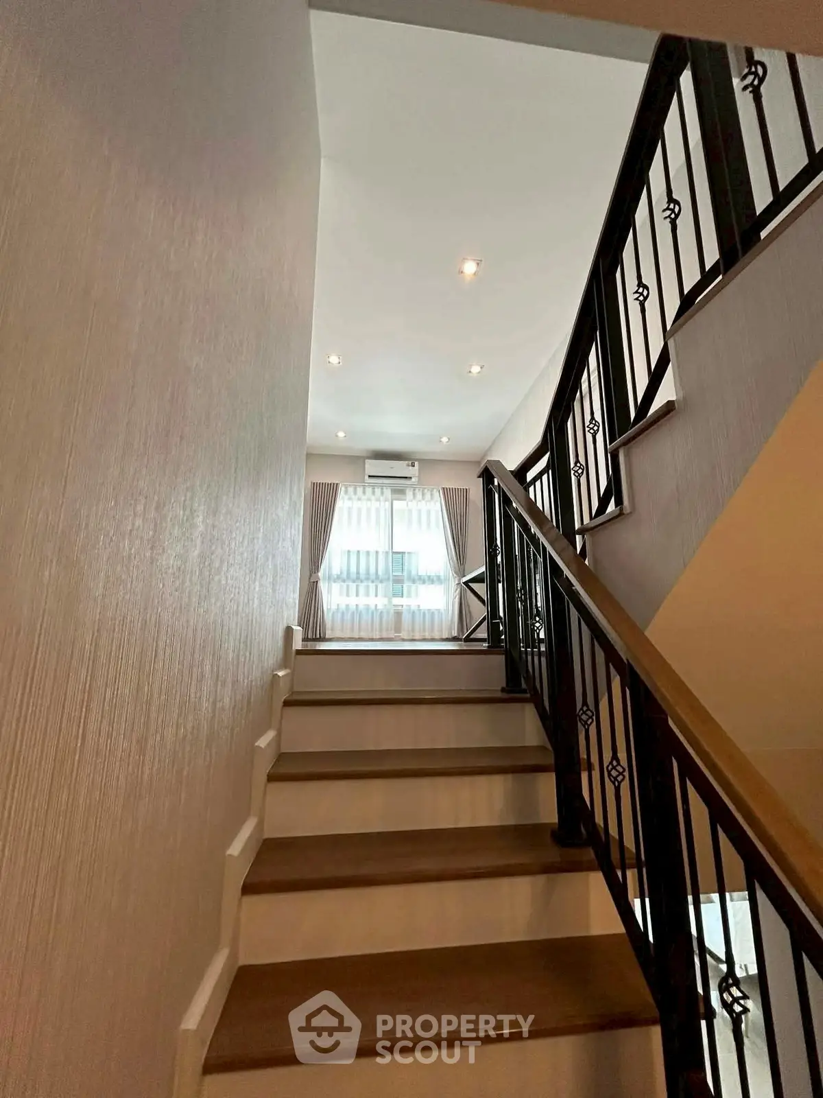 Elegant staircase with modern railing leading to a bright upper floor in a stylish home.