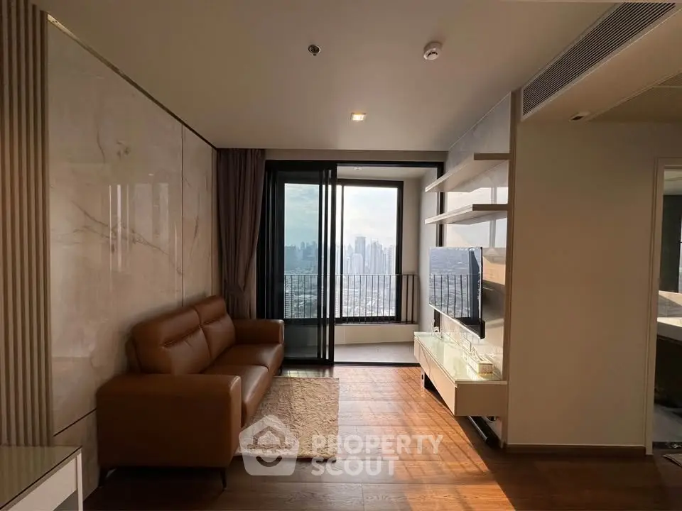Modern living room with city view, featuring a leather sofa and sleek TV setup.