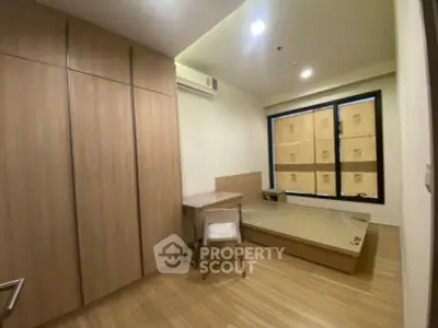 Modern bedroom with wooden flooring and built-in wardrobe, featuring a minimalist design.