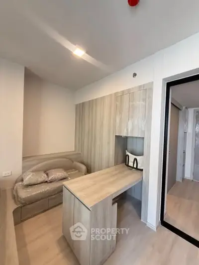 Modern compact kitchen with sleek wooden cabinetry and cozy seating area in a stylish apartment.