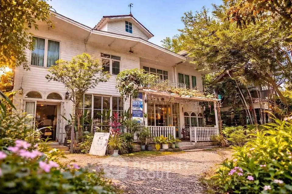 Charming two-story house with lush garden and inviting porch, perfect for serene living.