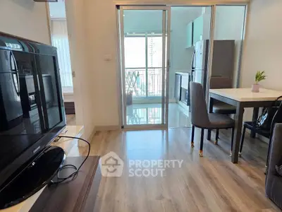 Modern apartment interior with open layout, featuring a sleek kitchen and cozy living area with balcony access.