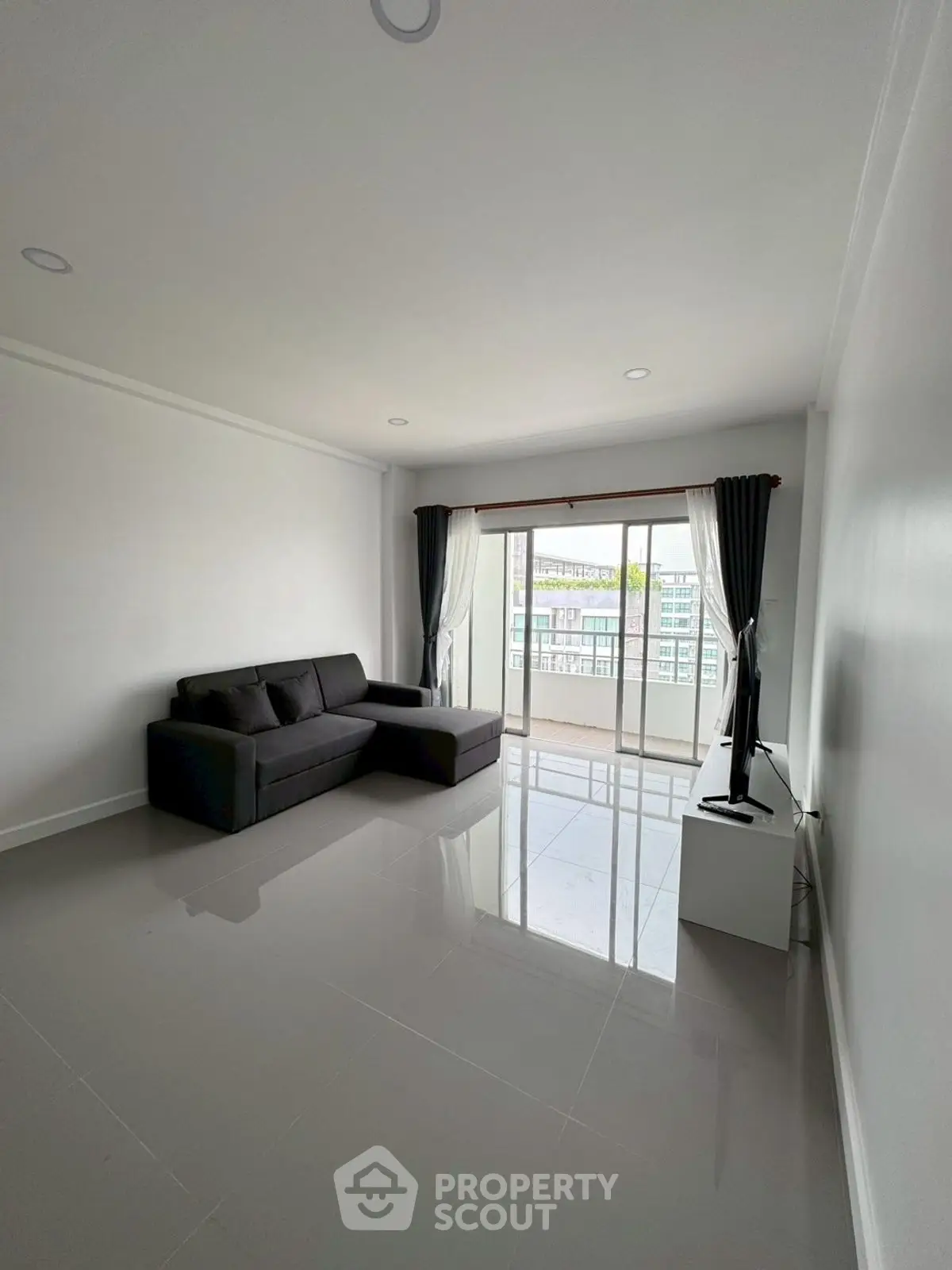 Spacious living room with modern sofa and large window offering city view.