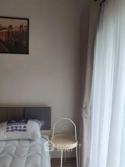 Cozy bedroom corner with soft lighting and modern decor, featuring a comfortable bed and sheer curtains.