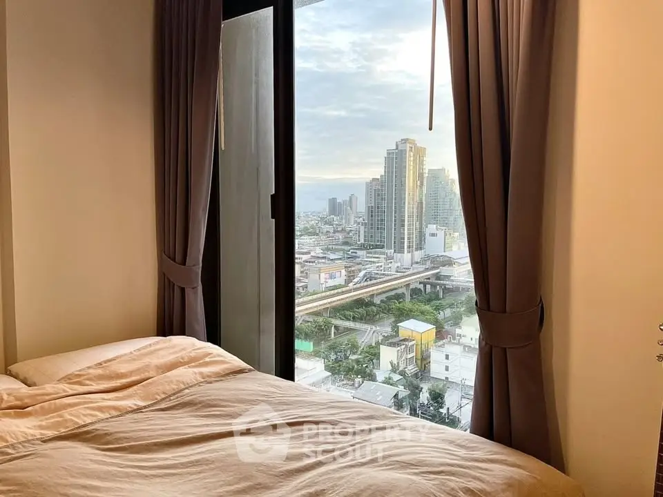 Cozy bedroom with stunning city view from large window, perfect urban retreat.
