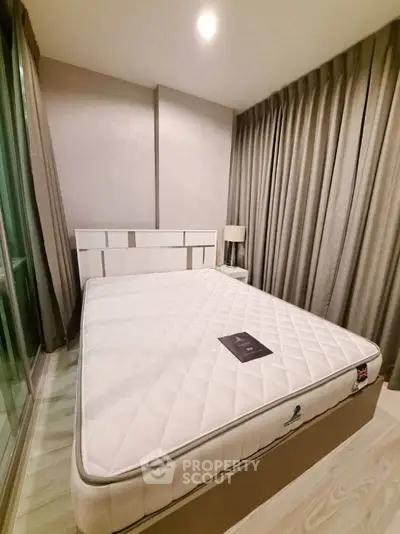 Modern bedroom with elegant decor and large window, featuring a comfortable mattress and stylish curtains.